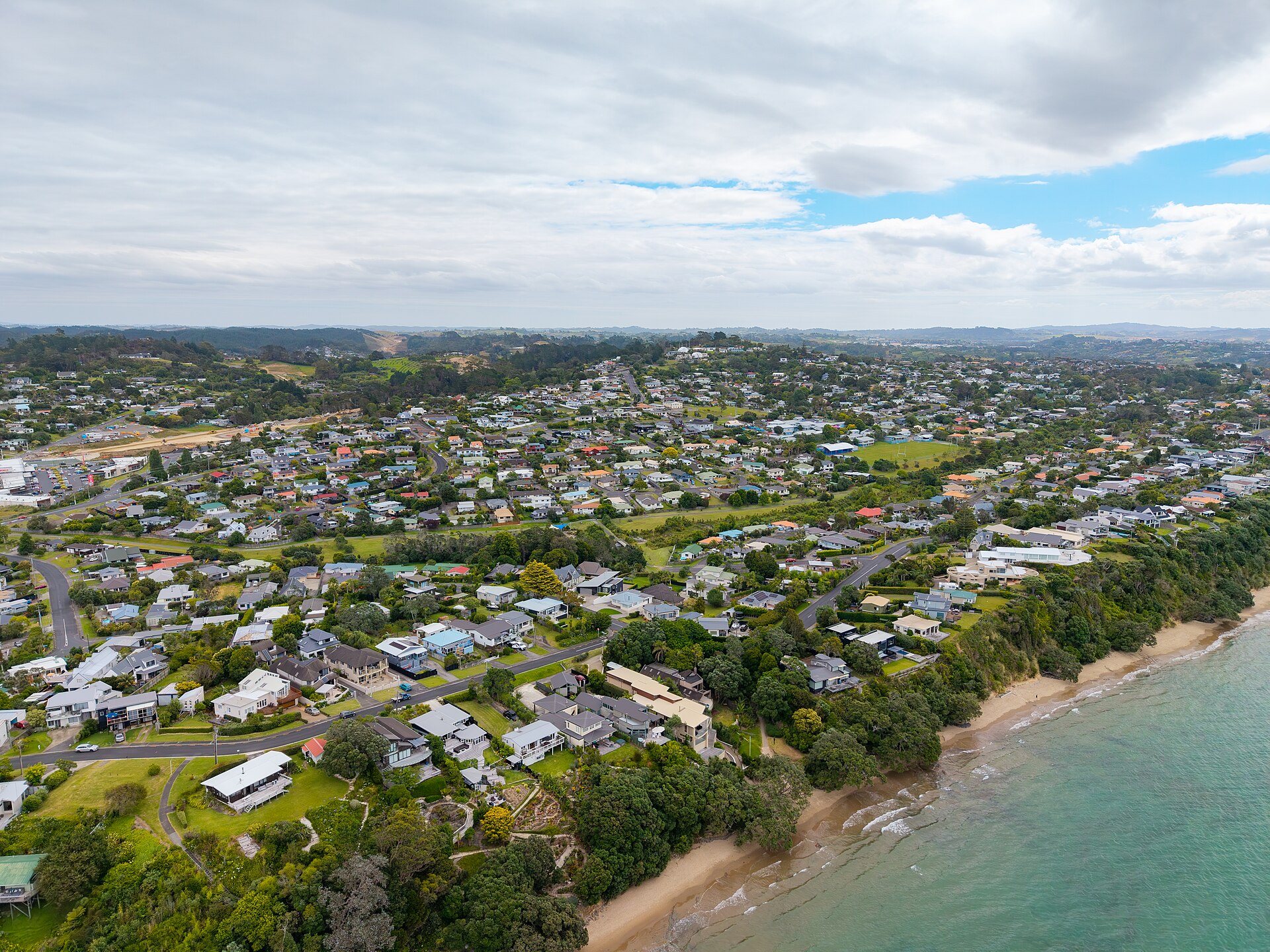 Aerial view of Stanmore Bay's streets and houses above the beach on the Hibiscus Coast