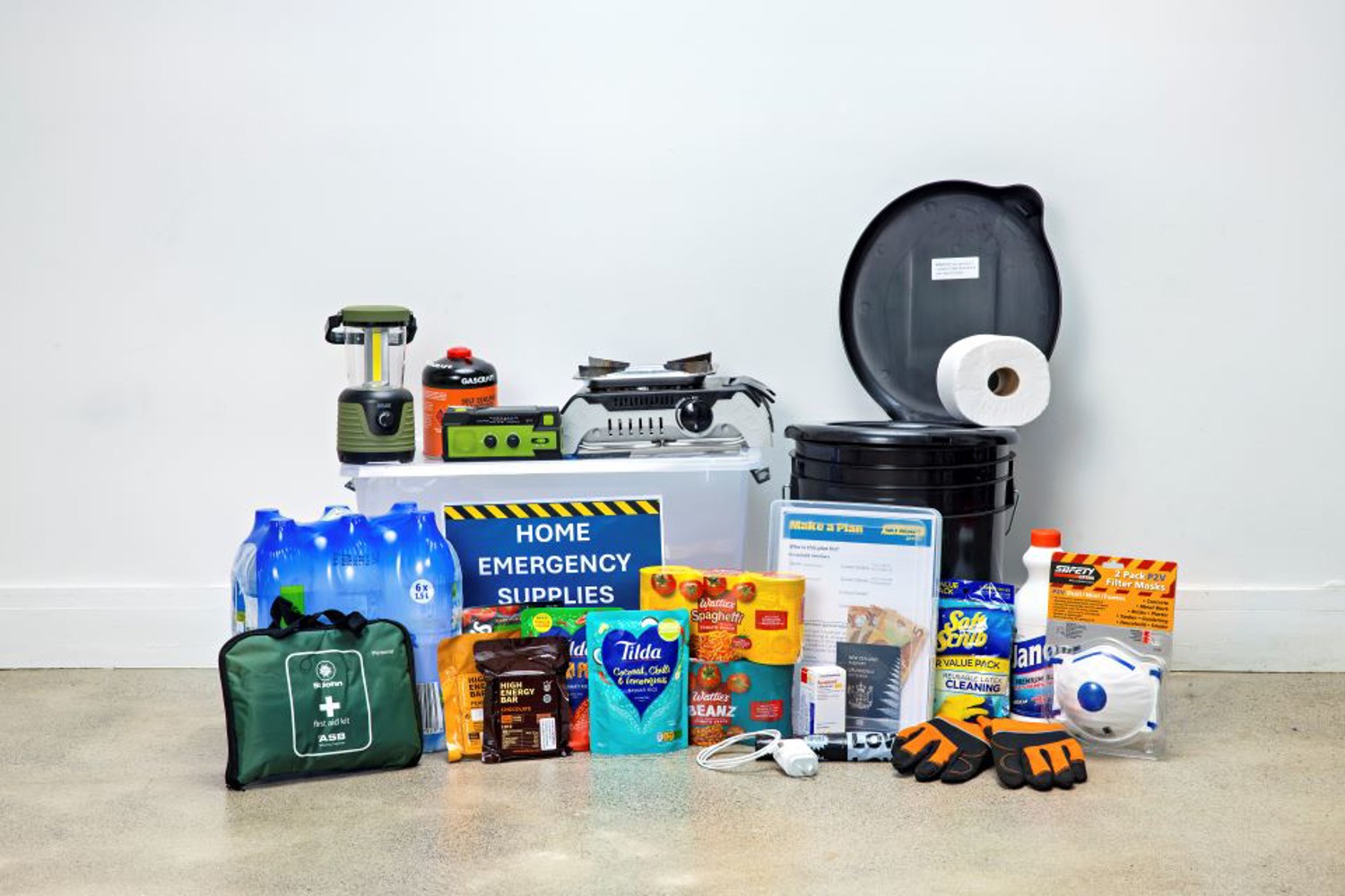Home emergency supplies laid out by Auckland Emergency Management — water containers, food, torch, batteries and a grab bag